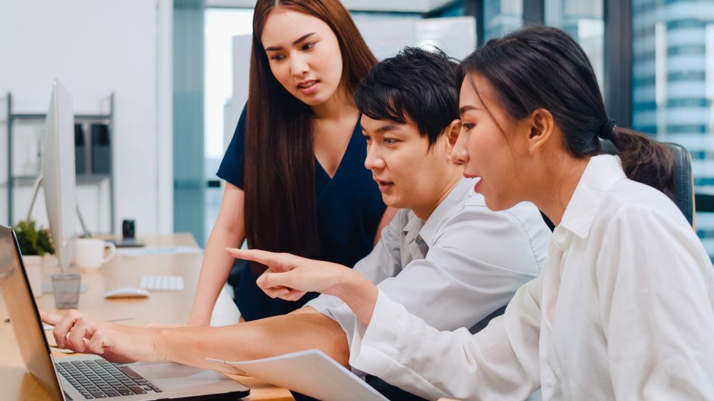 Tim kreatif berdiskusi di depan laptop untuk merancang video animasi sosialisasi edukatif